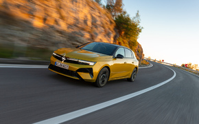 Gelber Opel Astra fahrend vor Steinwand von vorn fotografiert