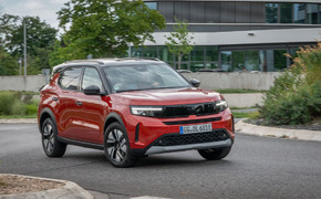 Opel Frontera Electric in der Standardlackierung Kanyon Orange Metallic fährt um Kreisverkehr