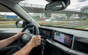 Fotoaufnahme von innen während der Fahrt in Richtung Tacho. Fahrer hat beide Hände am lenkrad.